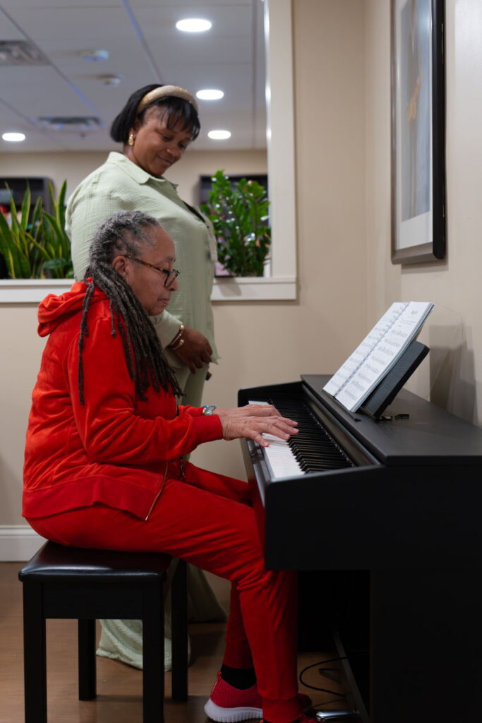 Old women in Memory care learning the piano with assistance.